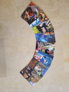 מניפה מעוקלת של כרטיסים מלבניים, שעליהם קולאז'ים של תמונות שונות, בהן נמר, אדם חובש כובע, ציפור ודמויות נוספות.