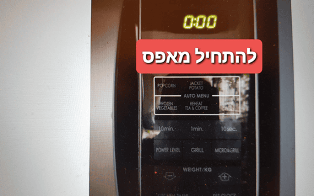 לוח הבקרה של המיקרוגל מציג את השעה 0:00 עם כיתוב גרפי אדום בעברית שמשמעותו “איפוס לאפס”.