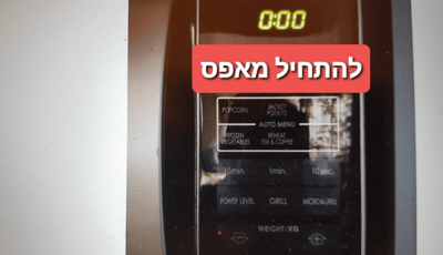 לוח הבקרה של המיקרוגל מציג את השעה 0:00 עם כיתוב גרפי אדום בעברית שמשמעותו “איפוס לאפס”.
